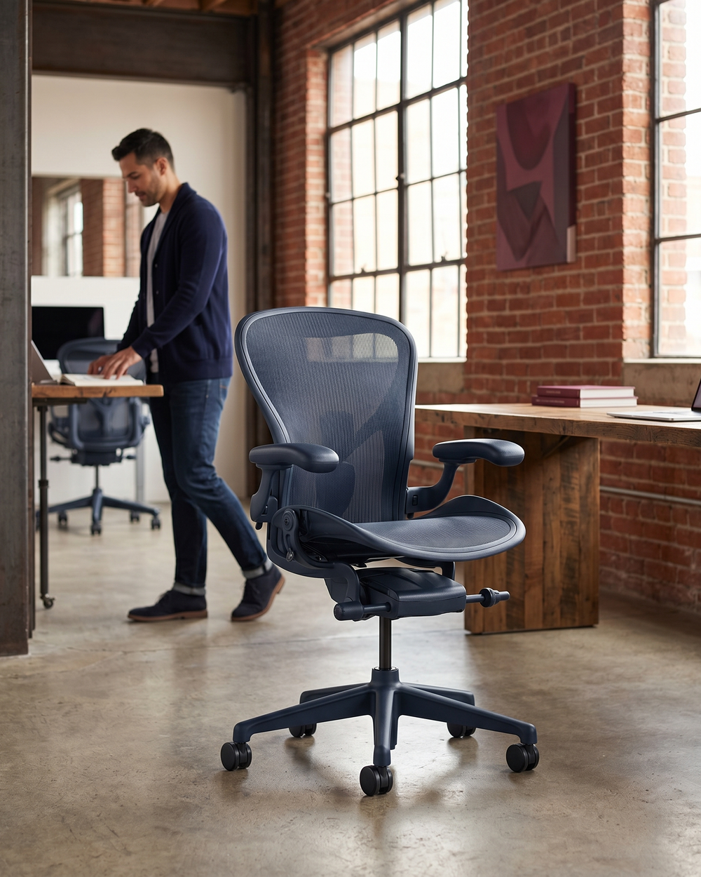Ergonomischer Bürostuhl in modernem Büro mit natürlichem Licht, Mann steht an Stehpult im Hintergrund.
