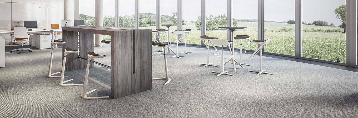 Moderne ergonomische Bürohocker und Tische in einem hellen, minimalistischen Raum mit großen Fenstern.