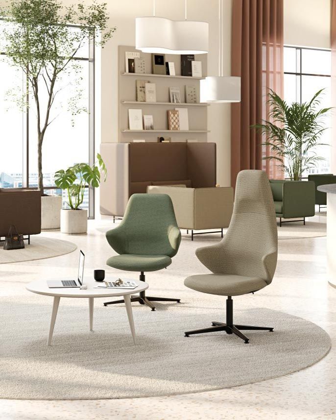 Moderne ergonomische Bürostühle und Couchtisch in einem hellen, gemütlichen Raum mit großen Fenstern und grünen Pflanzen.