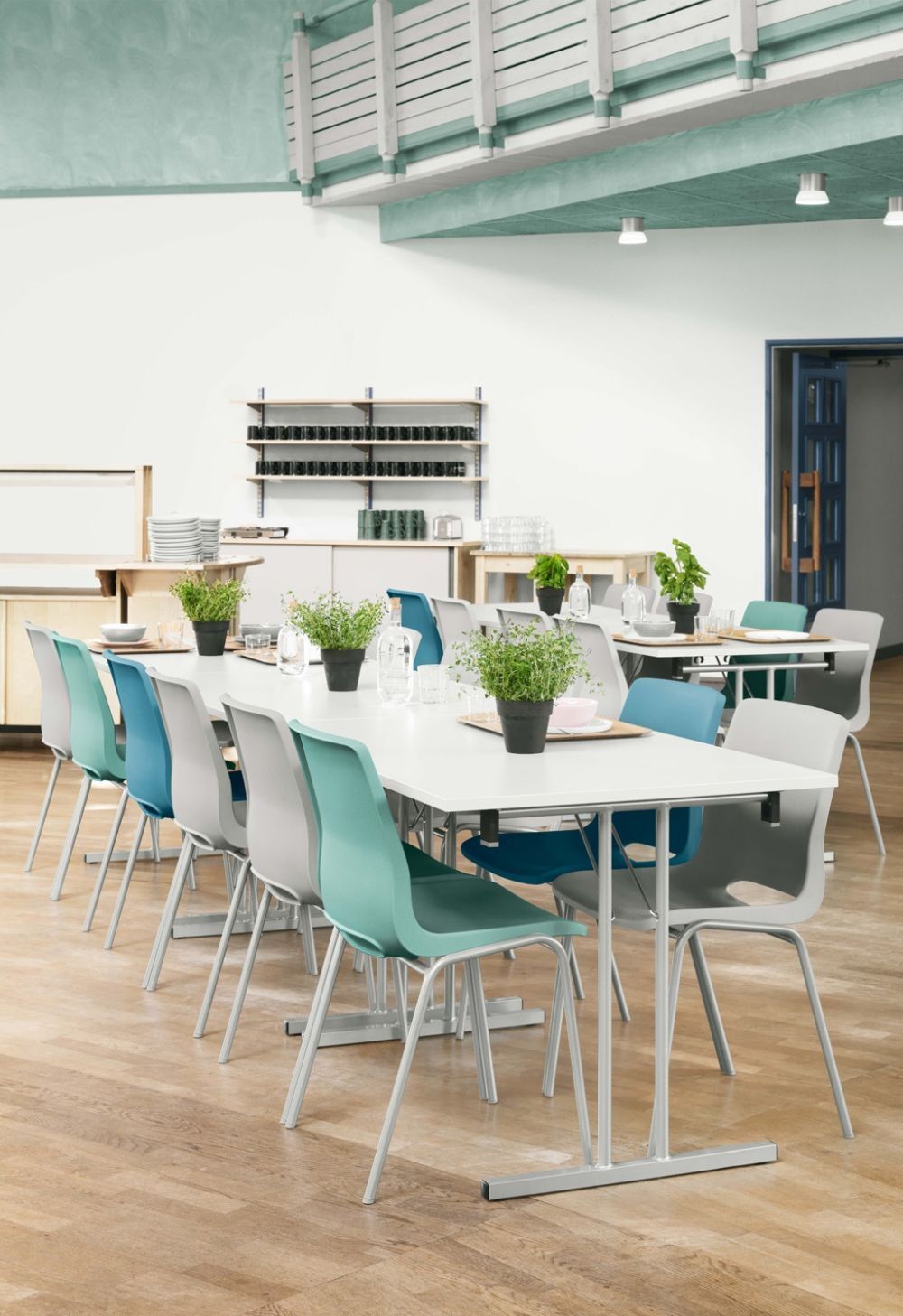 Moderne Cafeteria mit ergonomischen Stühlen in verschiedenen Farben und Pflanzen als Tischdekoration auf Holzboden.
