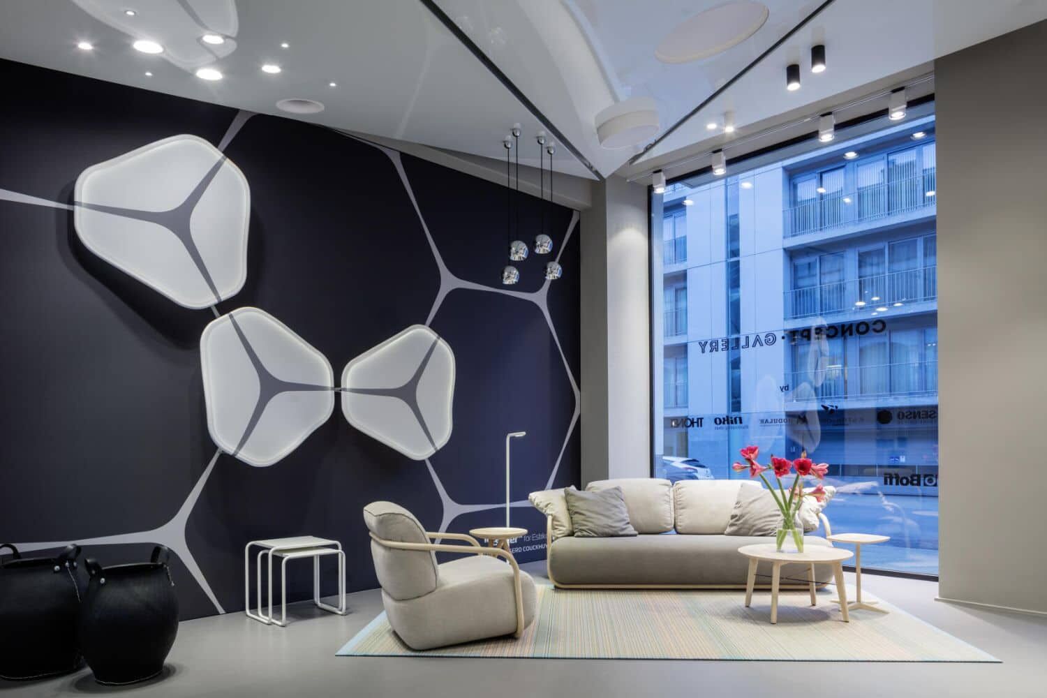 Moderne Lounge mit Designer-Sesseln, Sofa, dekorativer Wandkunst und Tisch mit Vase und Blumen.