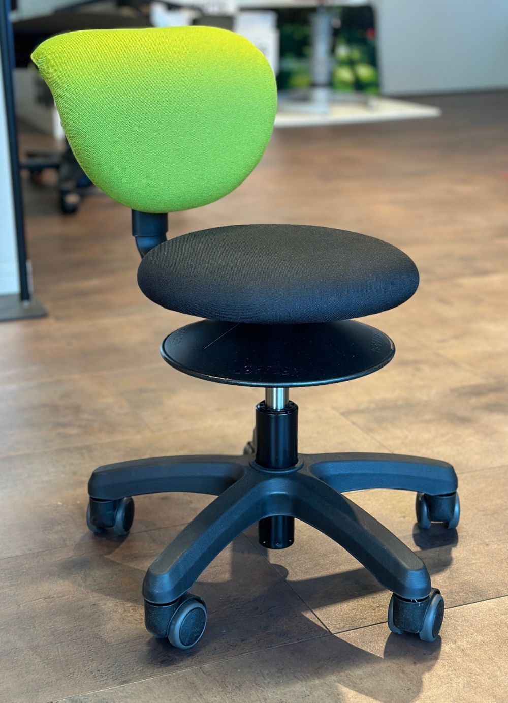 Ergonomischer Bürostuhl mit grünem Rückenlehne und schwarzem Sitz, auf Rollen für dynamisches Sitzen.