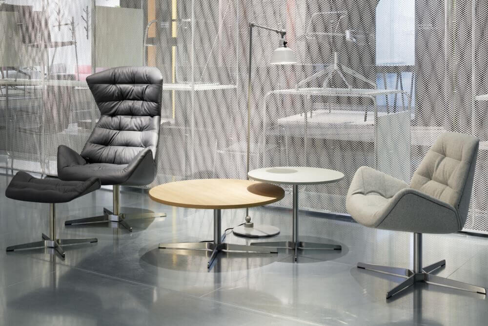 Moderne ergonomische Sessel und Couchtische in einem stilvollen, hell beleuchteten Raum mit Netzvorhang.