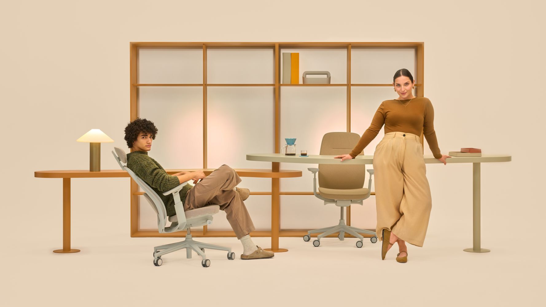 Zwei Personen in modernem Büro, Sitzen auf ergonomischen Stühlen, helle Einrichtung mit Holzregalen.
