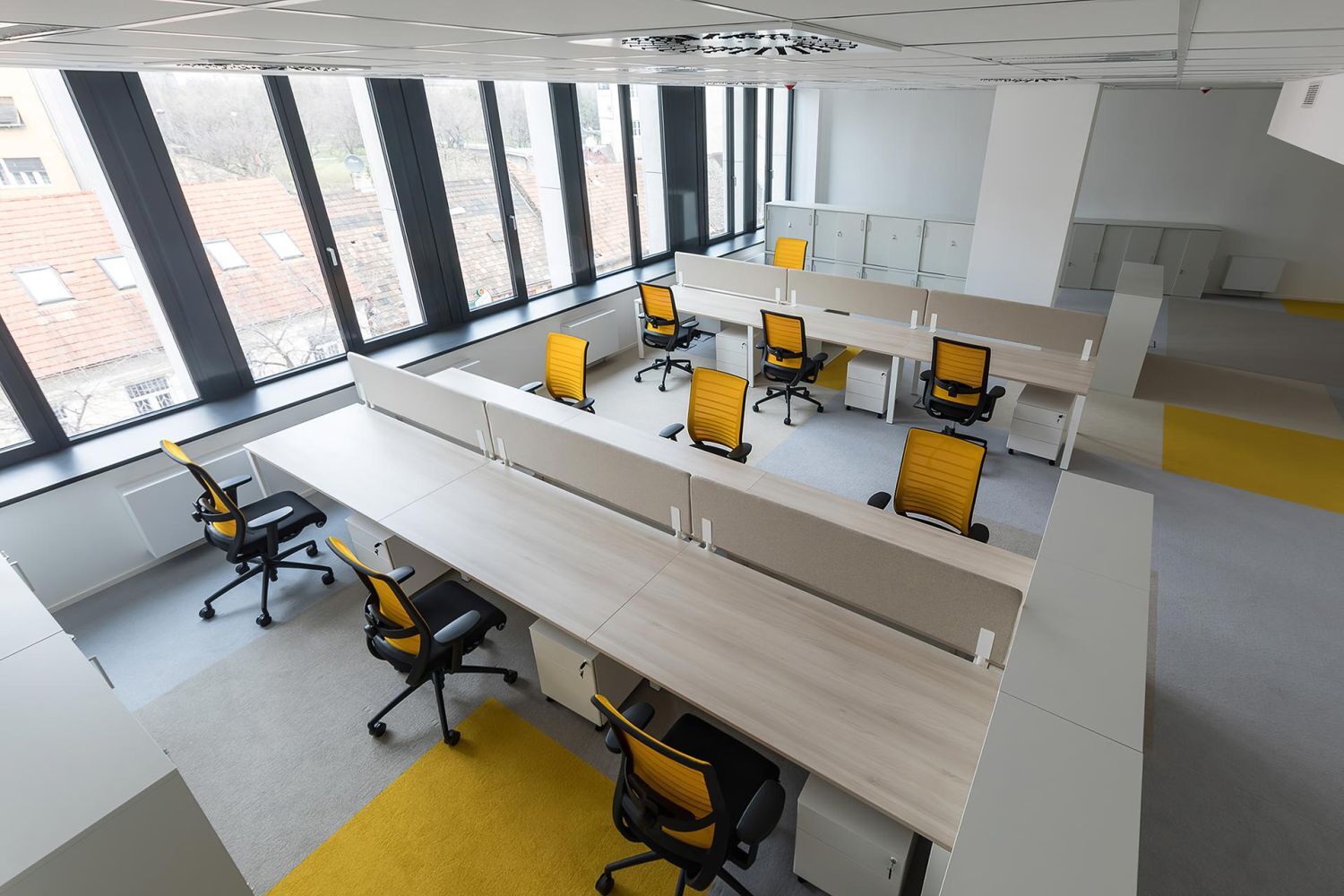 Moderne Büroeinrichtung mit ergonomischen Stühlen in leuchtendem Gelb und großen Fenstern für viel Tageslicht.