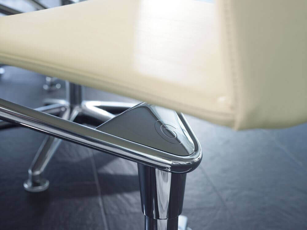 Detailansicht eines ergonomischen Stuhls mit verchromtem Gestell und anthrazitfarbenem Bedienelement.