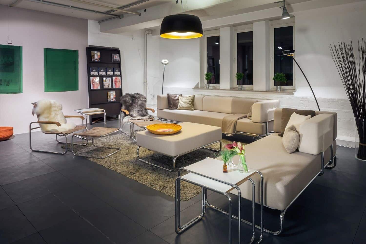 Moderner Wohnraum mit beigen Sofas, ergonomischen Stühlen und stilvoller Beleuchtung für dynamisches Sitzen.