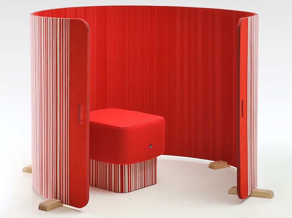 Moderner, roter akustischer Arbeitsplatzschirm mit integriertem Sitz für konzentriertes Arbeiten in offenen Büroumgebungen.