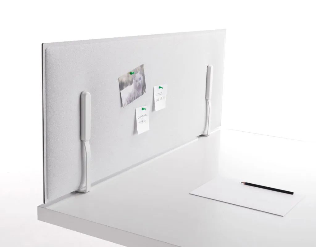 Weiße Schreibtischtrennwand mit befestigten Notizen, auf einem Schreibtisch mit Papier und Bleistift daneben.