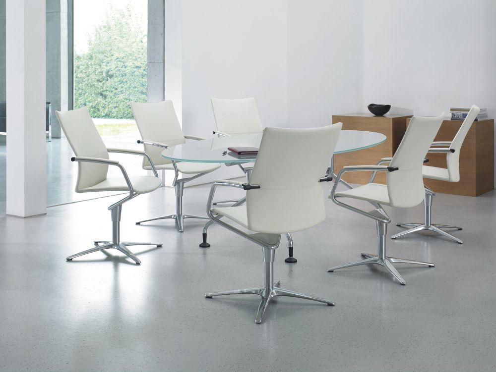 Moderner Konferenzraum mit sechs weißen, ergonomischen Stühlen um einen runden Glastisch.