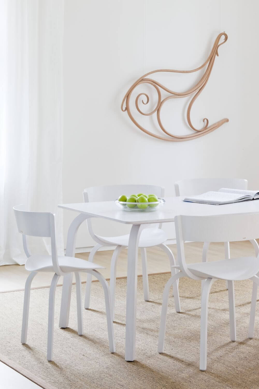 Moderner Essbereich mit weißen Stühlen, Tisch und Dekoration an der Wand; minimalistisch und elegant eingerichtet.