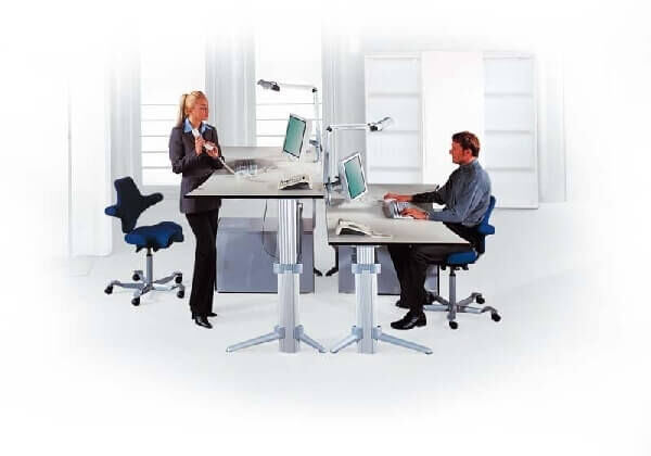 Zwei Personen an höhenverstellbaren Schreibtischen, zeigen ergonomische Sitz- und Stehlösungen für das Büro.