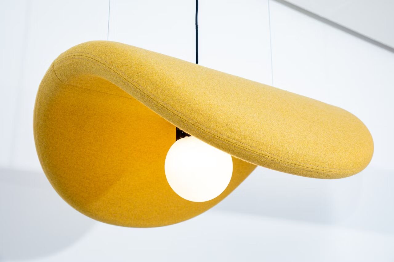 Moderne gelbe Hängelampe mit ungewöhnlicher Form und sichtbarem Leuchtmittel, geeignet für stilvolle Arbeitsumgebungen.