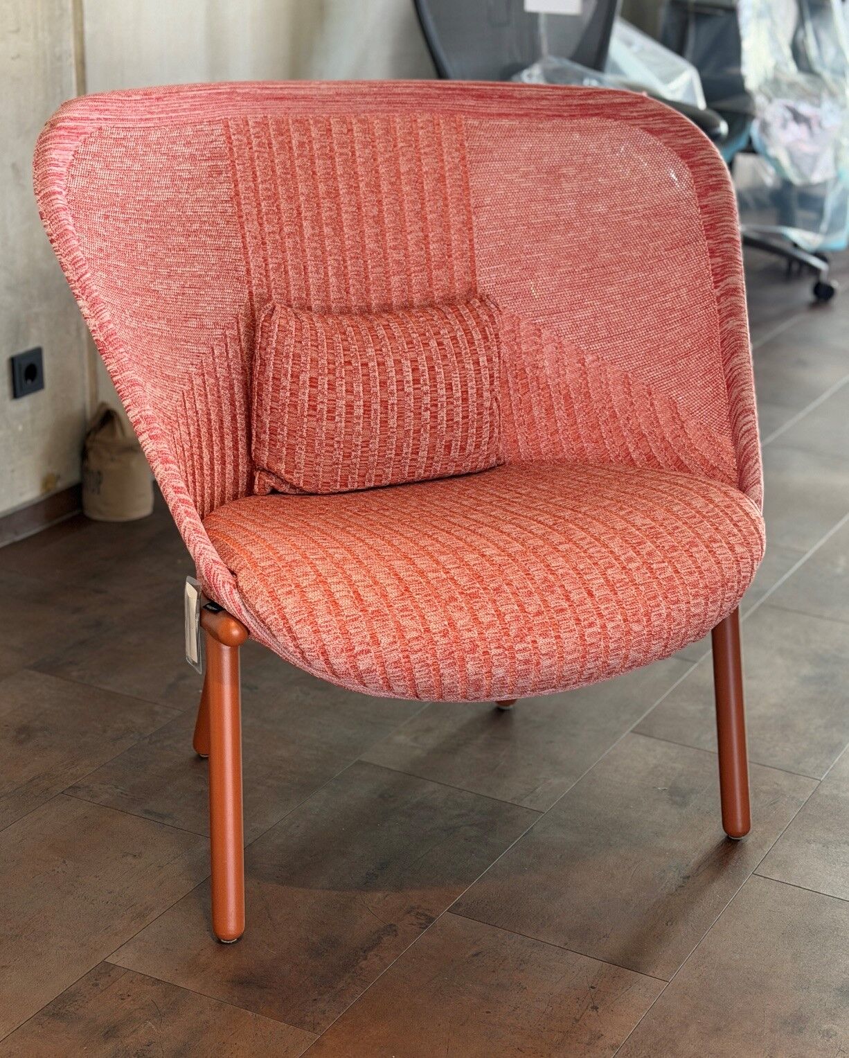 Roter ergonomischer Sessel mit gepolstertem Kissen, modernem Design und Metallbeinen auf Fliesenboden.