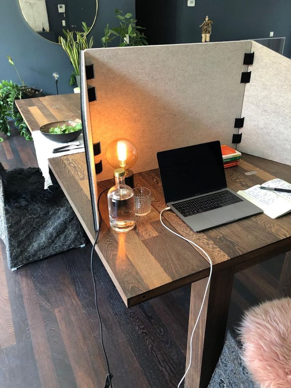 Arbeitsplatz zu Hause mit Laptop, dividiere Trennwand, Lampe und Pflanze auf einem dunklen Holztisch.