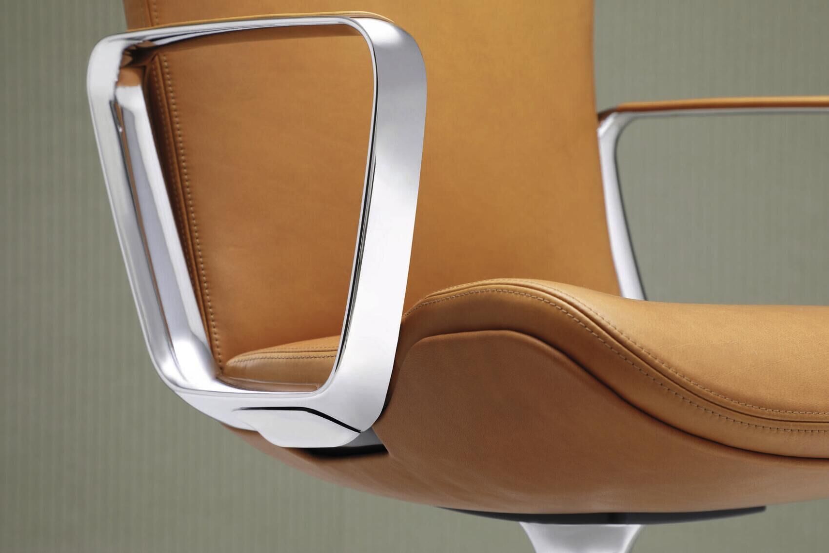 Detail eines ergonomischen Bürostuhls mit orangener Lederpolsterung und silbernem Metallarmlehnen-Design.