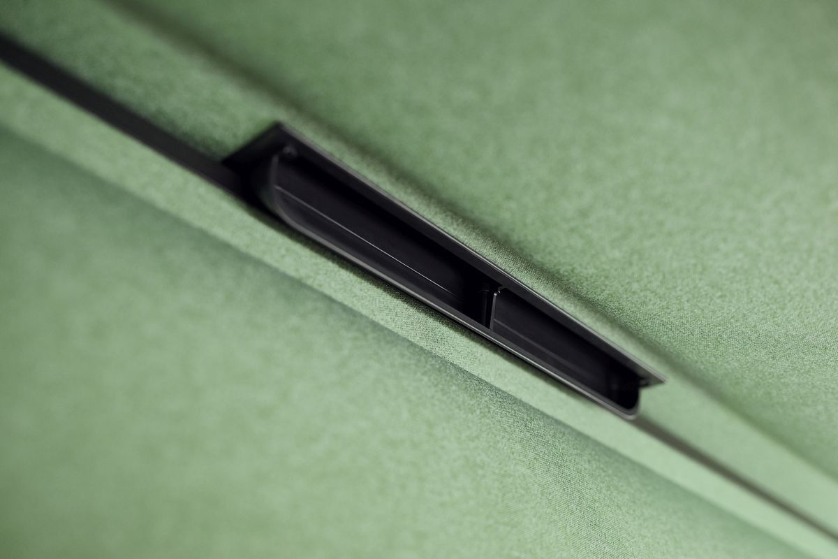 Nahaufnahme einer schlanken, schwarzen Schiene auf mintgrünem Stoff, Teil eines modernen Bürostuhls.