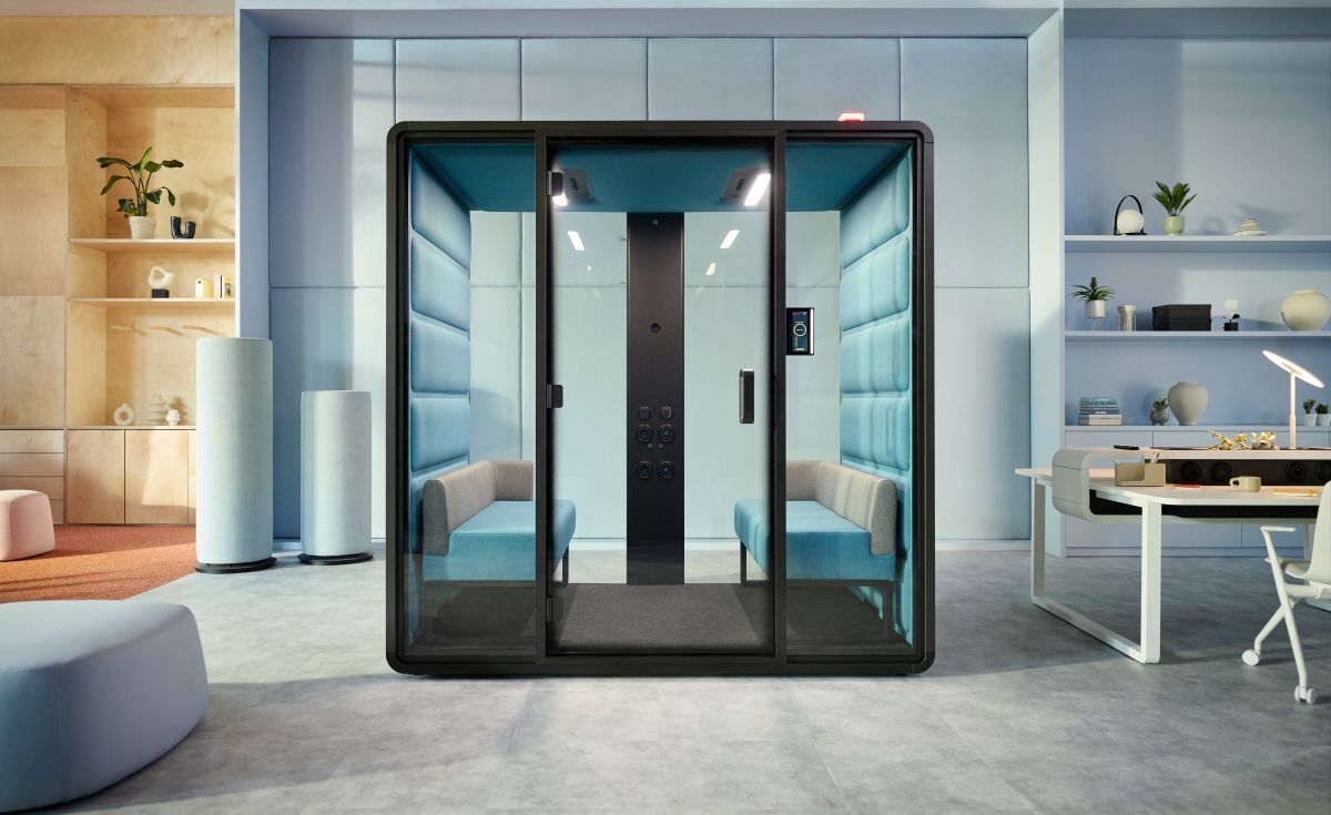 Moderne Bürokabine mit Glaswänden und blauen Polstern in einem stilvollen, ergonomischen Arbeitsbereich.