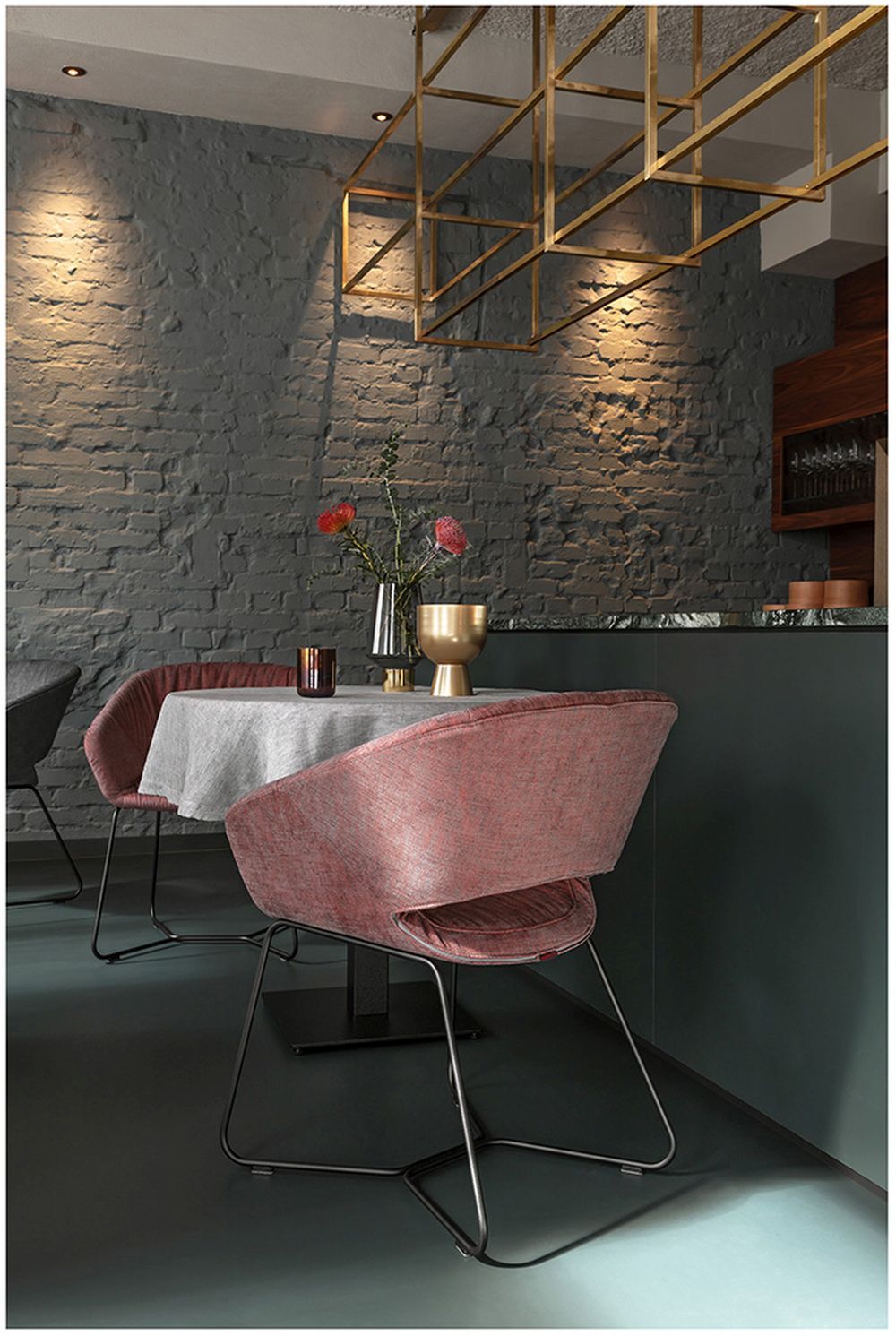 Moderner Essbereich mit eleganten Stühlen, Blumenvasen und stilvollem Beleuchtungselemente an einer grauen Backsteinwand.