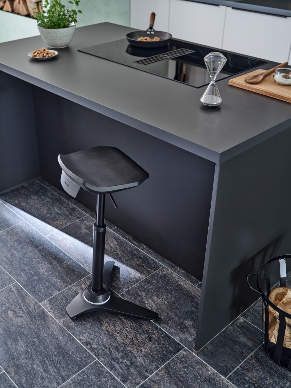 Moderner höhenverstellbarer Hocker in einer stilvollen Küche mit minimalistischer Einrichtung, neben einer Arbeitsplatte.