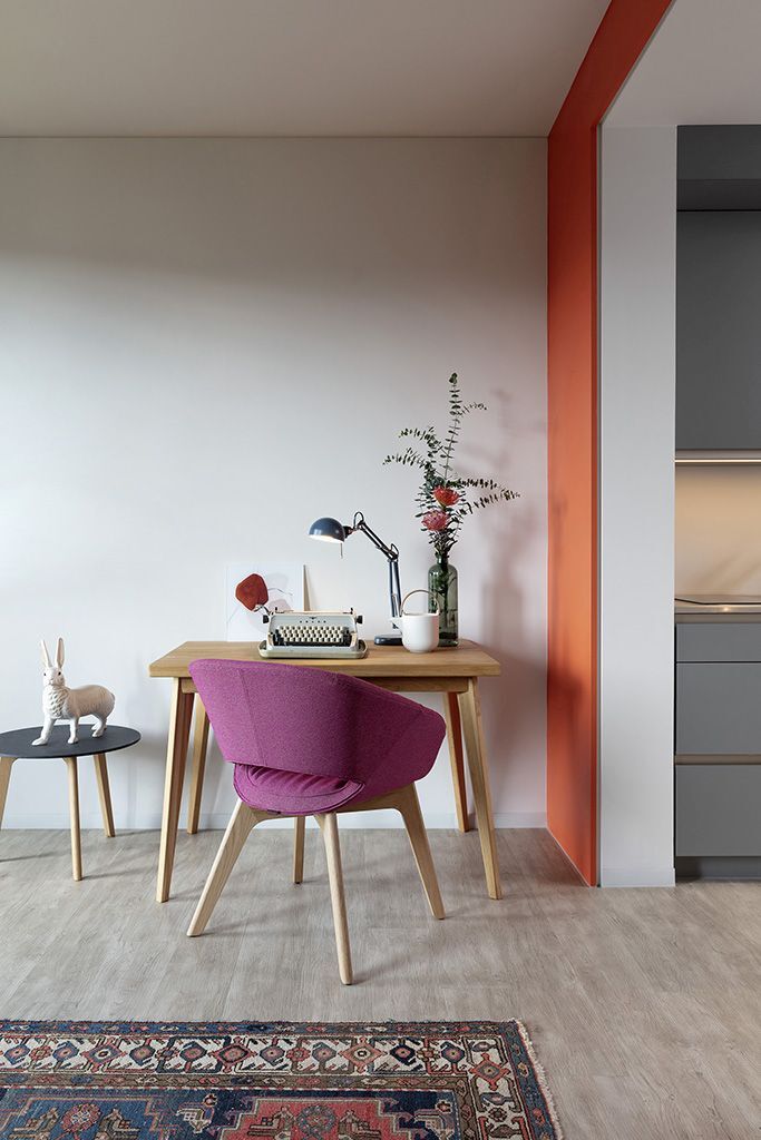 Moderner Arbeitsplatz mit ergonomischem Stuhl, Holzschreibtisch, Schreibmaschine und Dekoration im Büro oder Homeoffice.