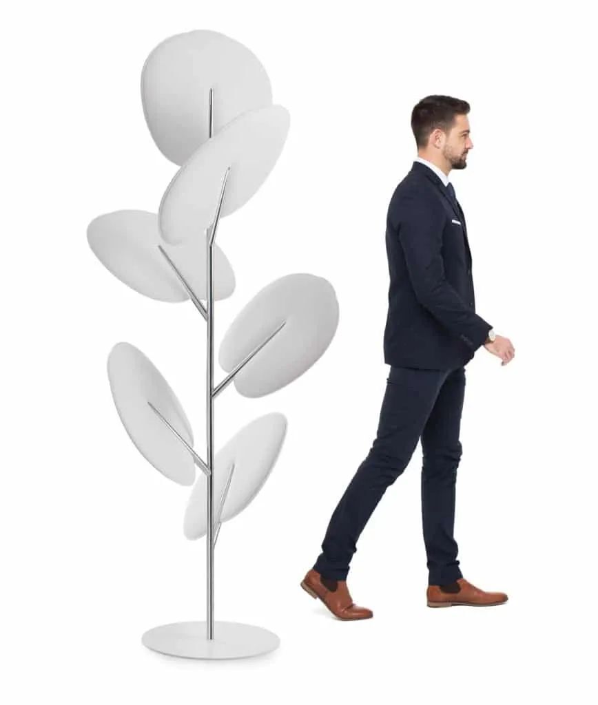 Ein Mann im Anzug geht neben einer modernen, blattförmigen Raumtrennung in Weiß auf weißem Hintergrund.