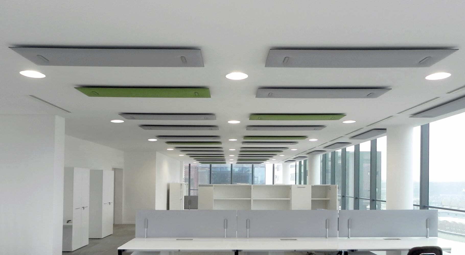 Modernes Büro mit ergonomischen Arbeitsplätzen, großen Fenstern und schallabsorbierenden Paneelen an der Decke.