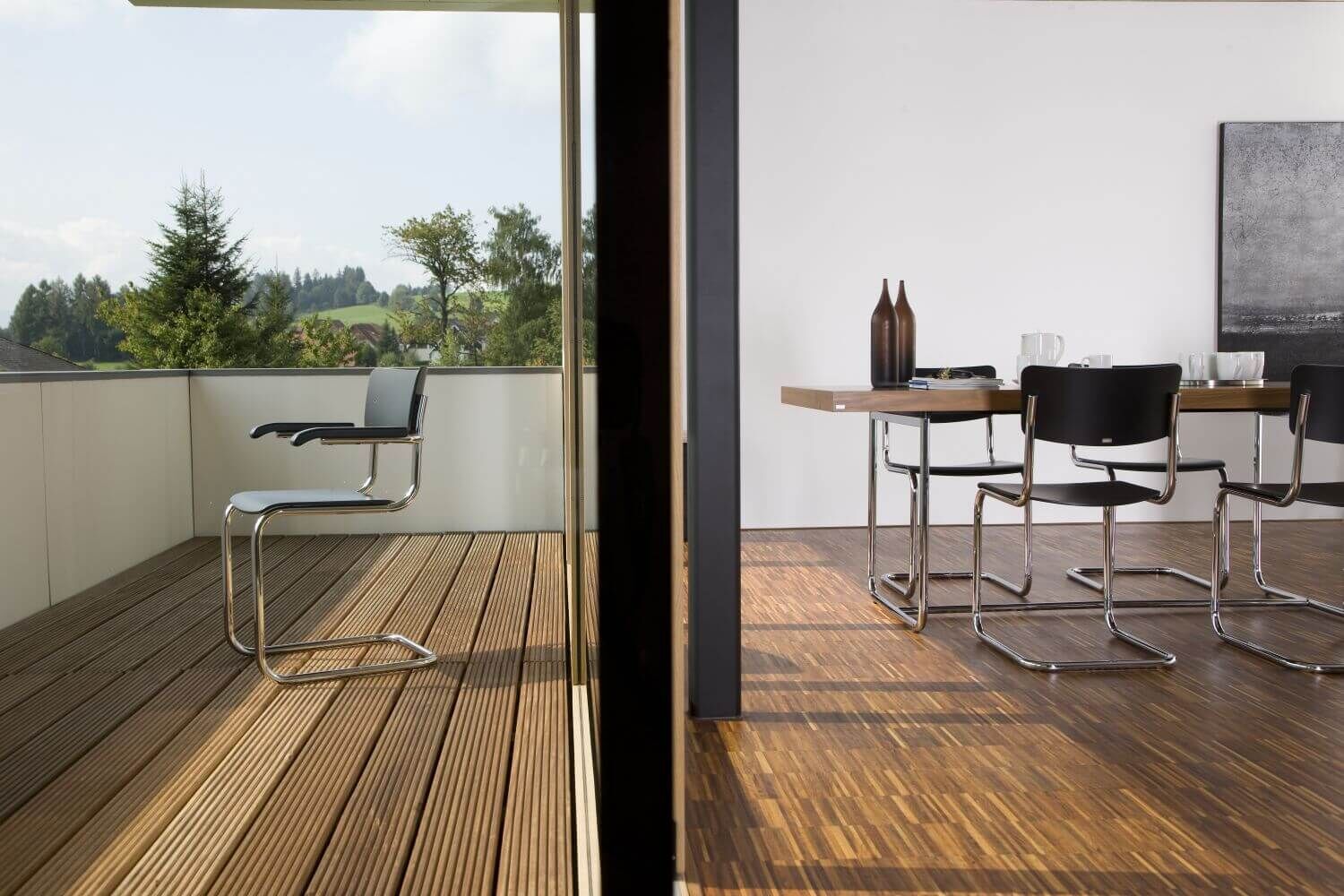 Elegantes Esszimmer mit modernen ergonomischen Stühlen, Holzboden und Blick auf eine Terrasse.