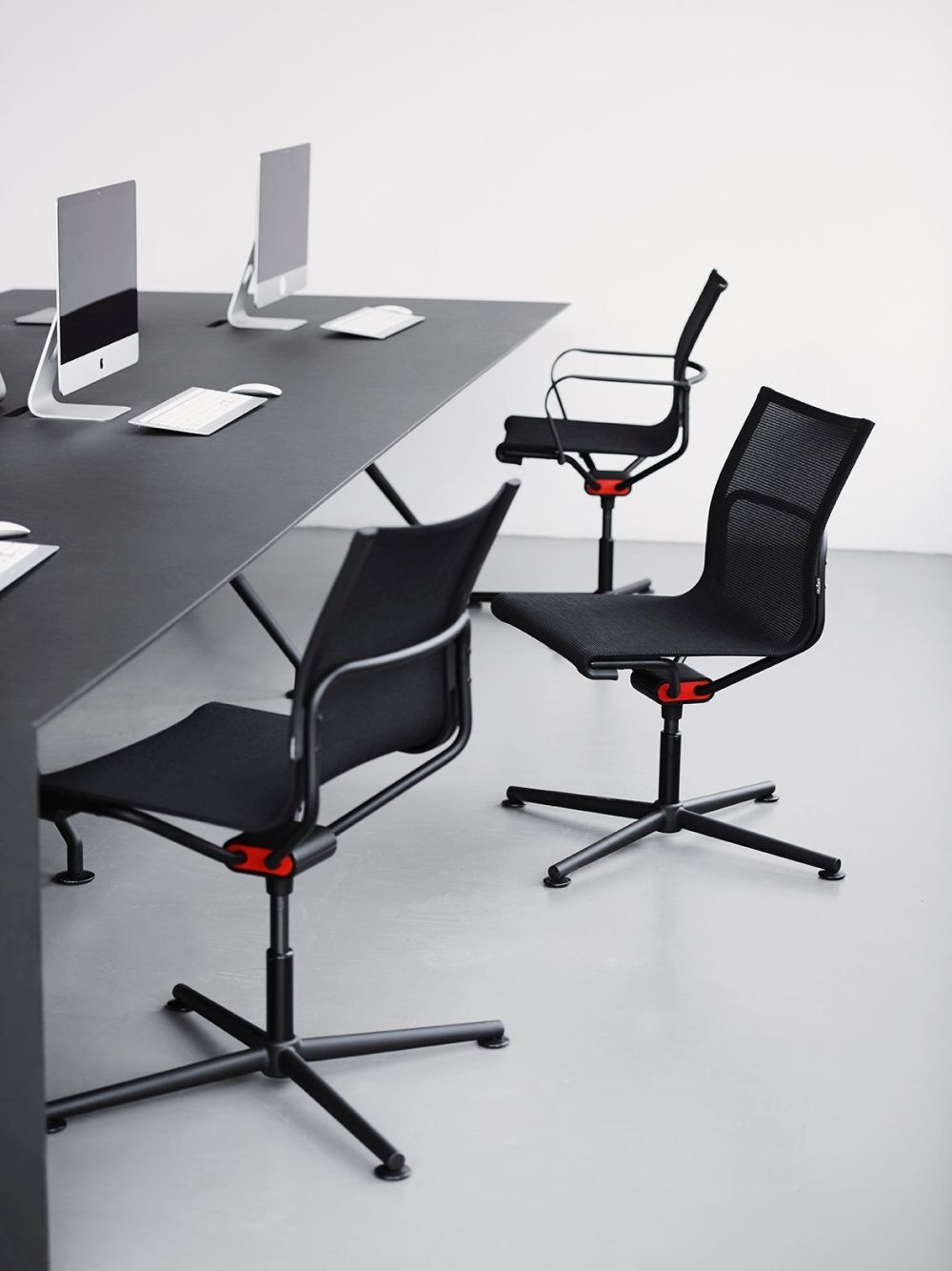 Moderne ergonomische Bürostühle und Computer auf einem eleganten Schreibtisch in einem minimalistischen Büro.