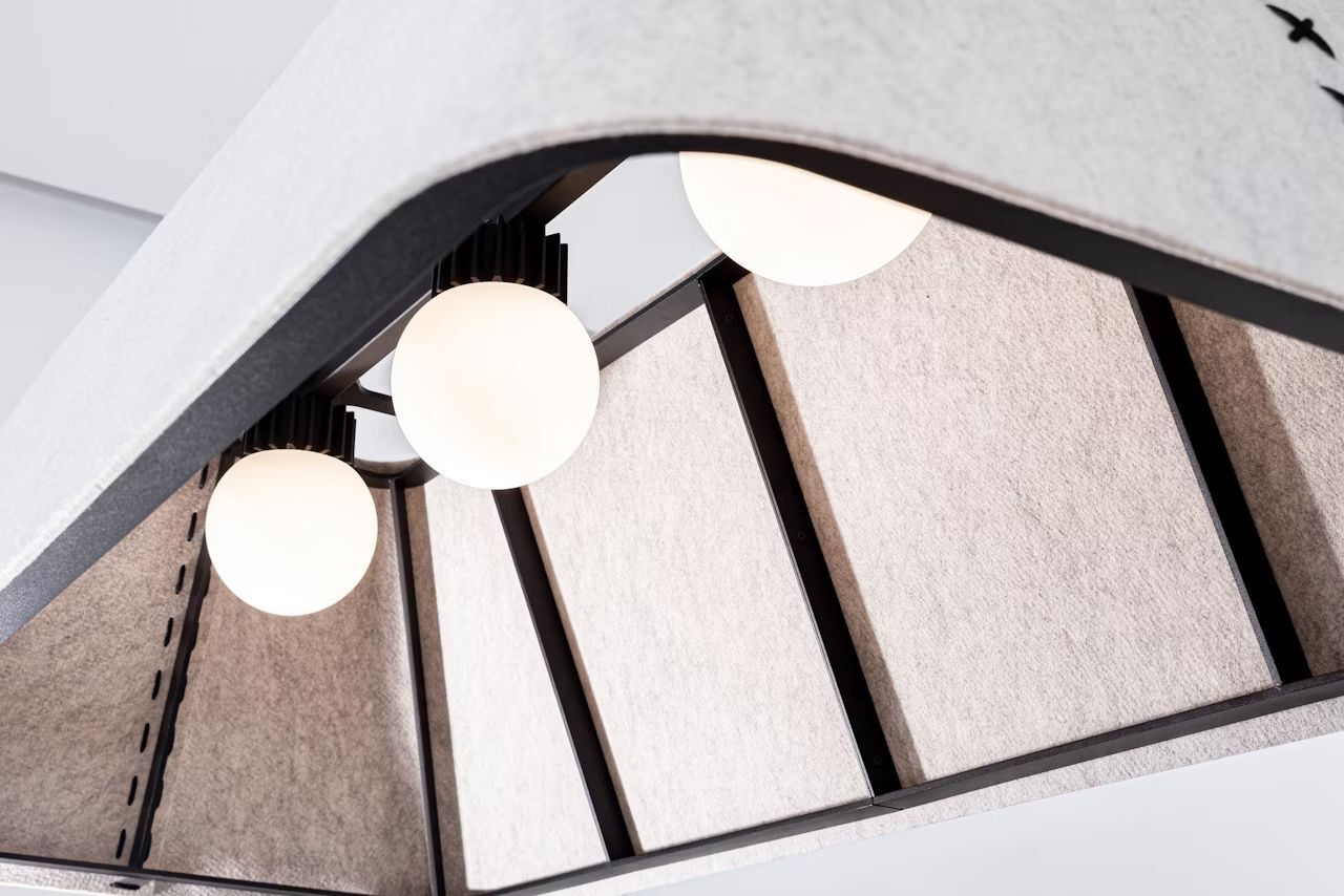 Moderne, ergonomische Hängelampe mit drei runden Glühbirnen und schallabsorbierenden Stoffpaneelen.