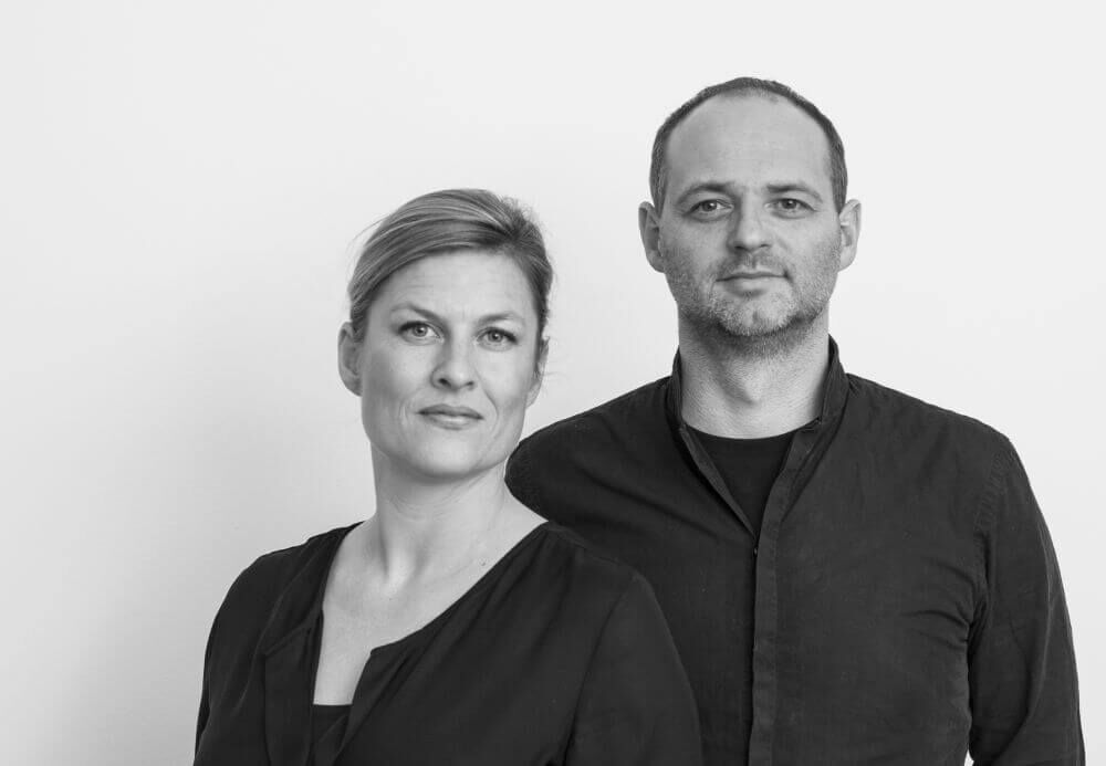 Porträt eines Mannes und einer Frau in schwarzer Kleidung, beide schauen freundlich in die Kamera.