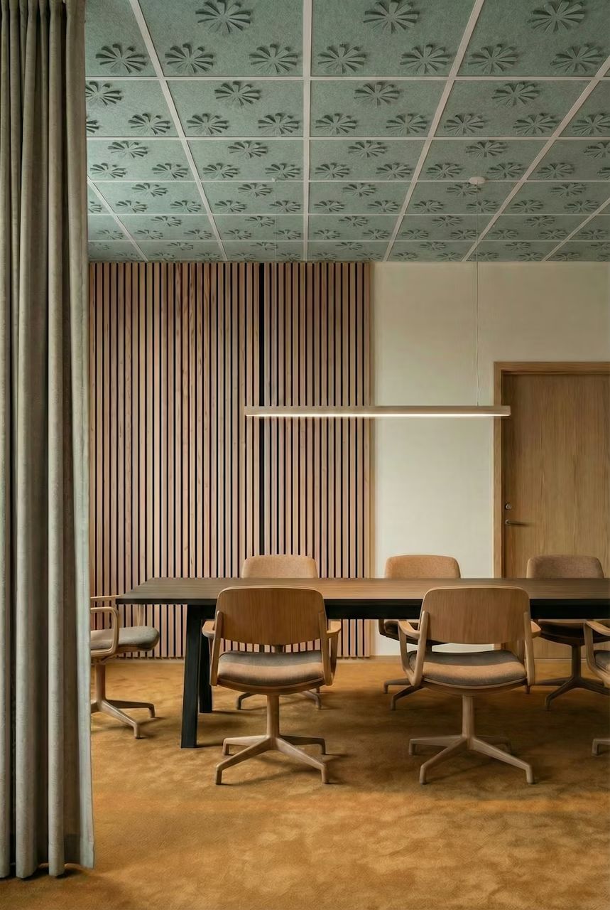 Moderner Konferenzraum mit ergonomischen Bürostühlen, Holzverkleidung und dekorativer Decke in elegantem Design.