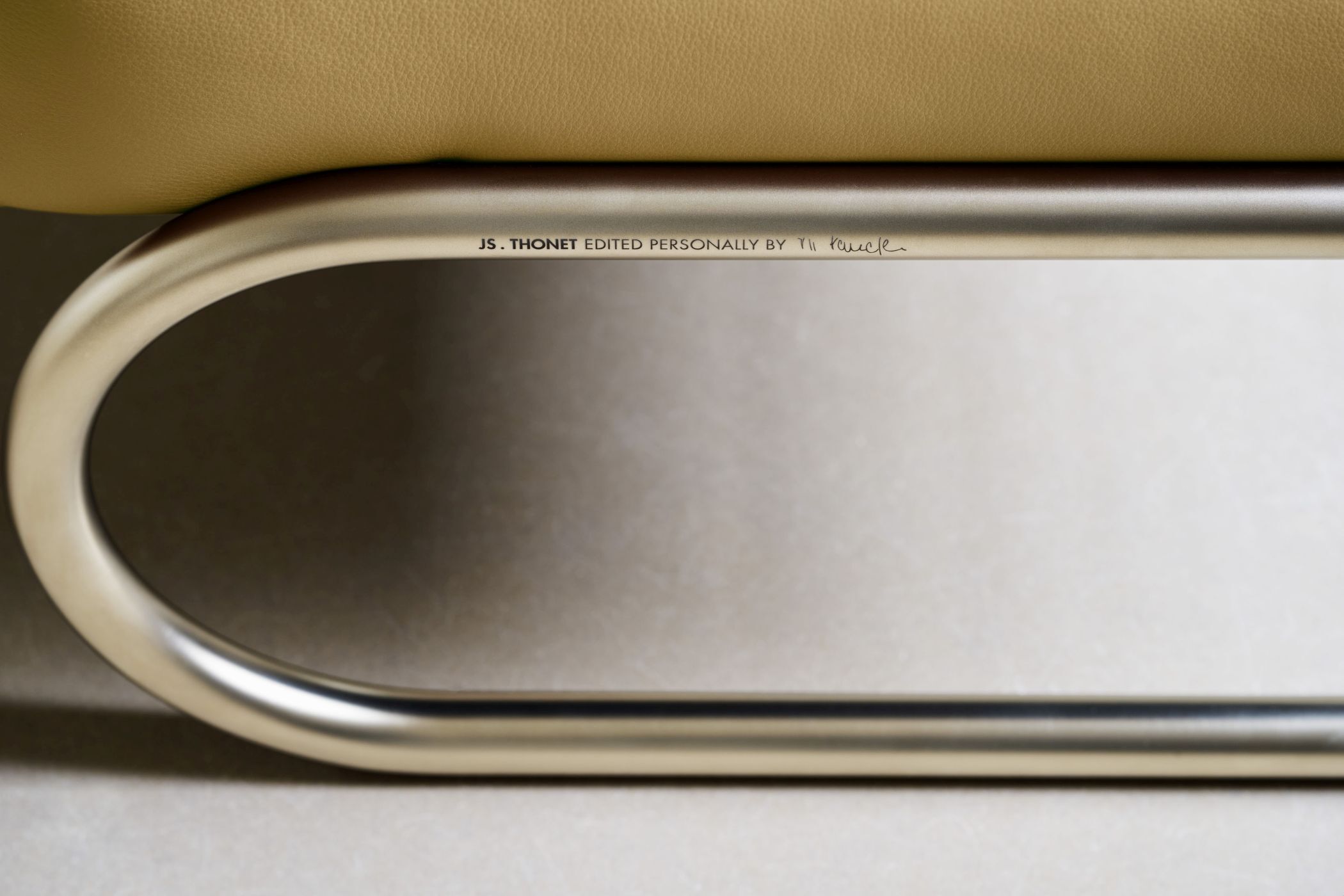 Detail einer gebogenen Metallbasis eines ergonomischen Stuhls mit eingravierter Aufschrift von JS Thonet.