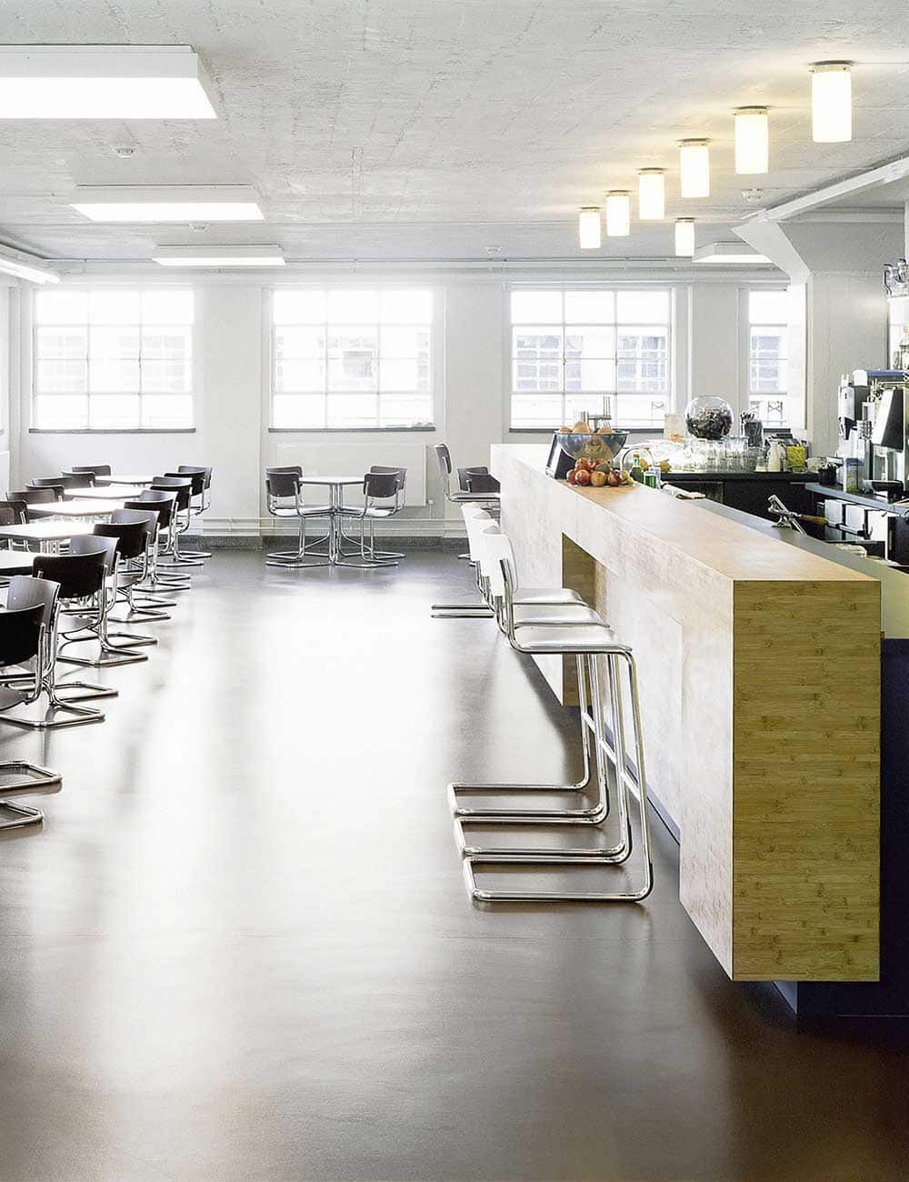 Moderner, heller Büroraum mit ergonomischen Stühlen und einem langen Tresen aus Holz.