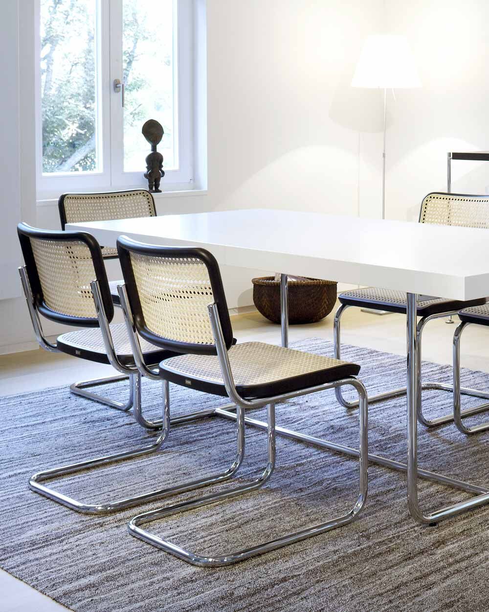 Eleganter Besprechungsraum mit modernen Freischwinger-Stühlen und einem weißen Tisch auf grauem Teppich.
