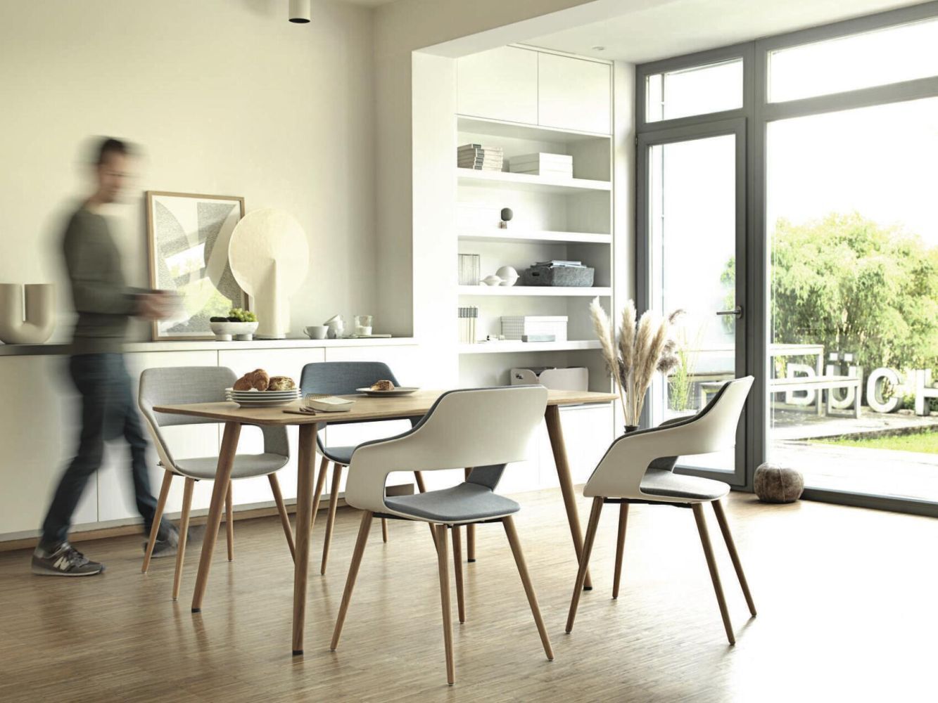 Moderne Esszimmermöbel mit Holztisch, ergonomischen Stühlen und großer Fensteransicht in hellem Raum.