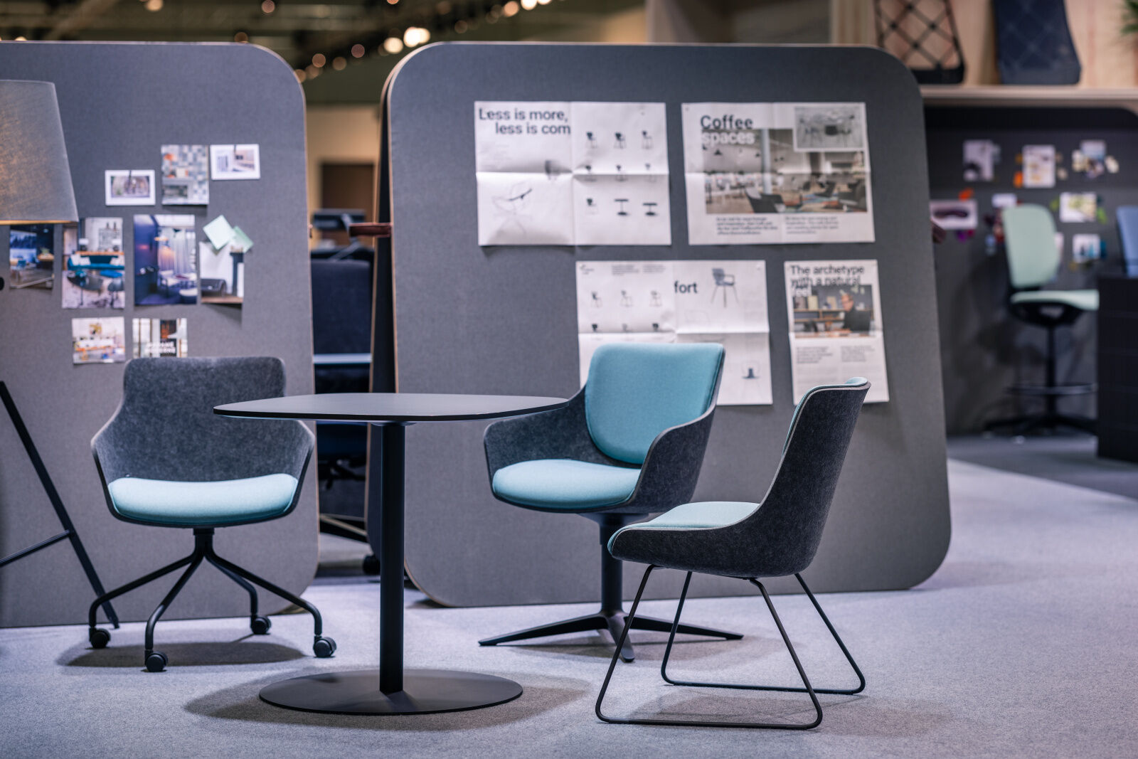 Moderne ergonomische Bürostühle um einen runden Tisch, mit Infotafeln im Hintergrund.