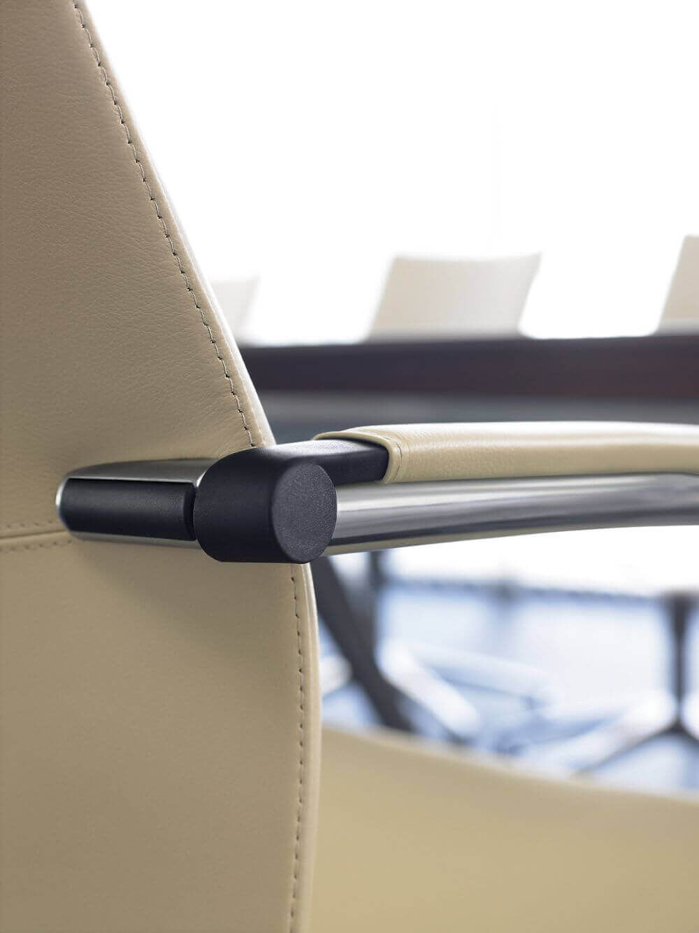 Nahaufnahme eines hochwertigen ergonomischen Bürostuhl-Armlehne mit hellem Lederbezug und Metallakzenten.