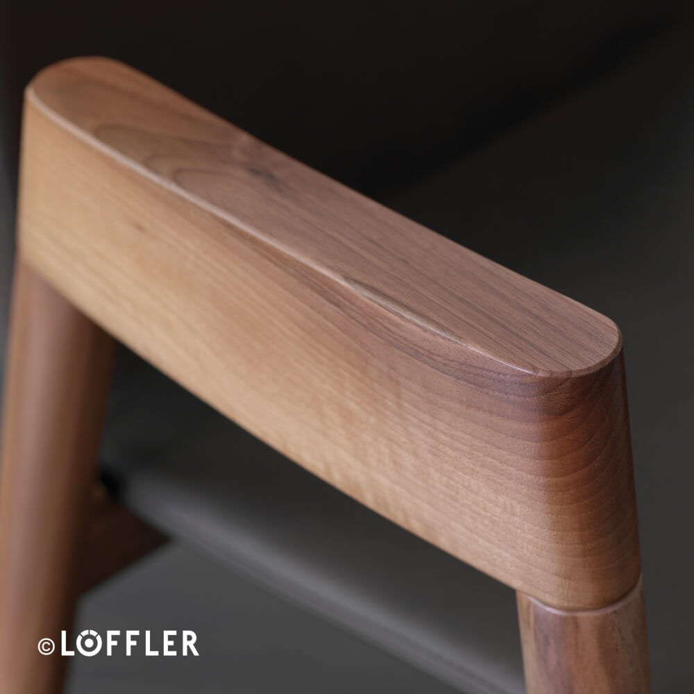 Nahaufnahme einer ergonomischen Holzarmlehne eines Bürostuhls, zeigt die feine Maserung und glatte Verarbeitung.