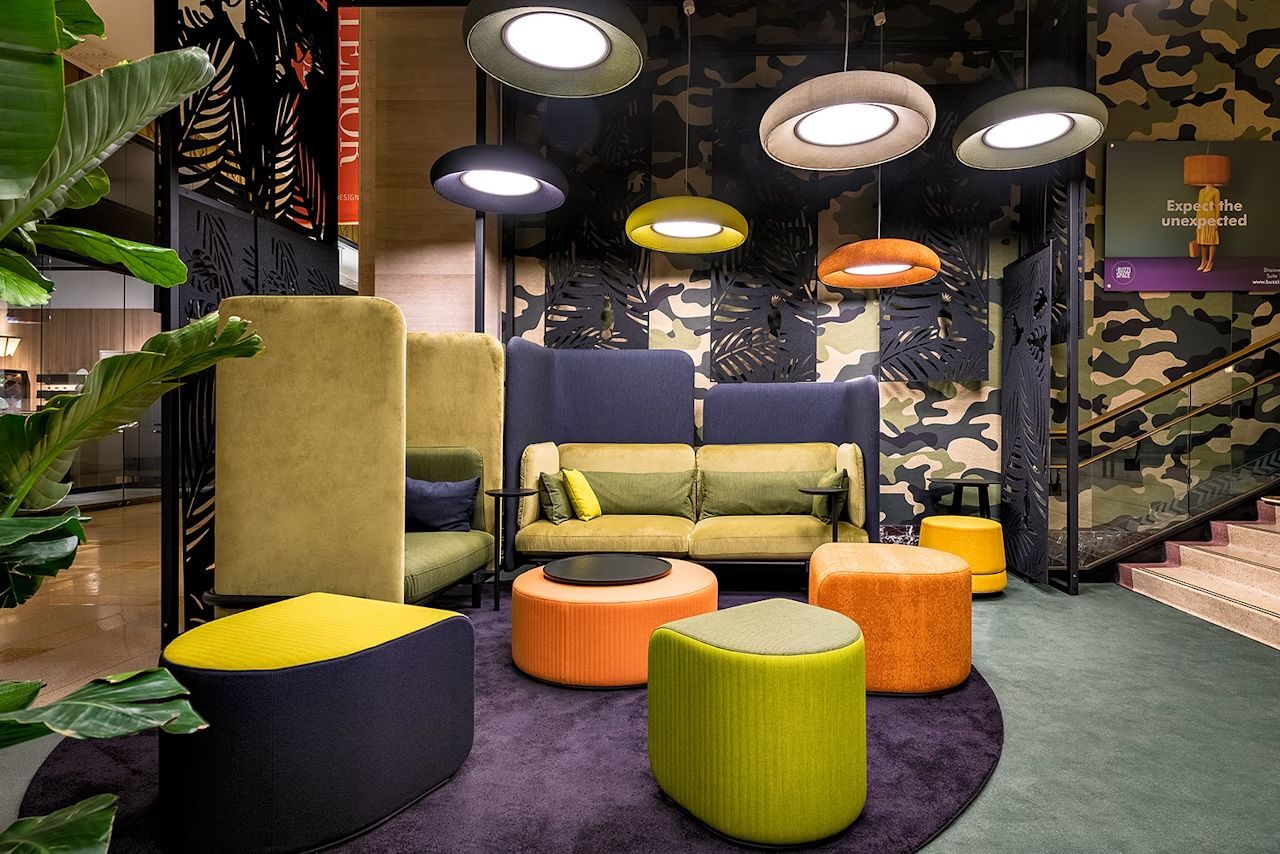 Moderne Lounge mit ergonomischen Sesseln, farbigen Hockern und innovativer Beleuchtung im Camouflage-Design.