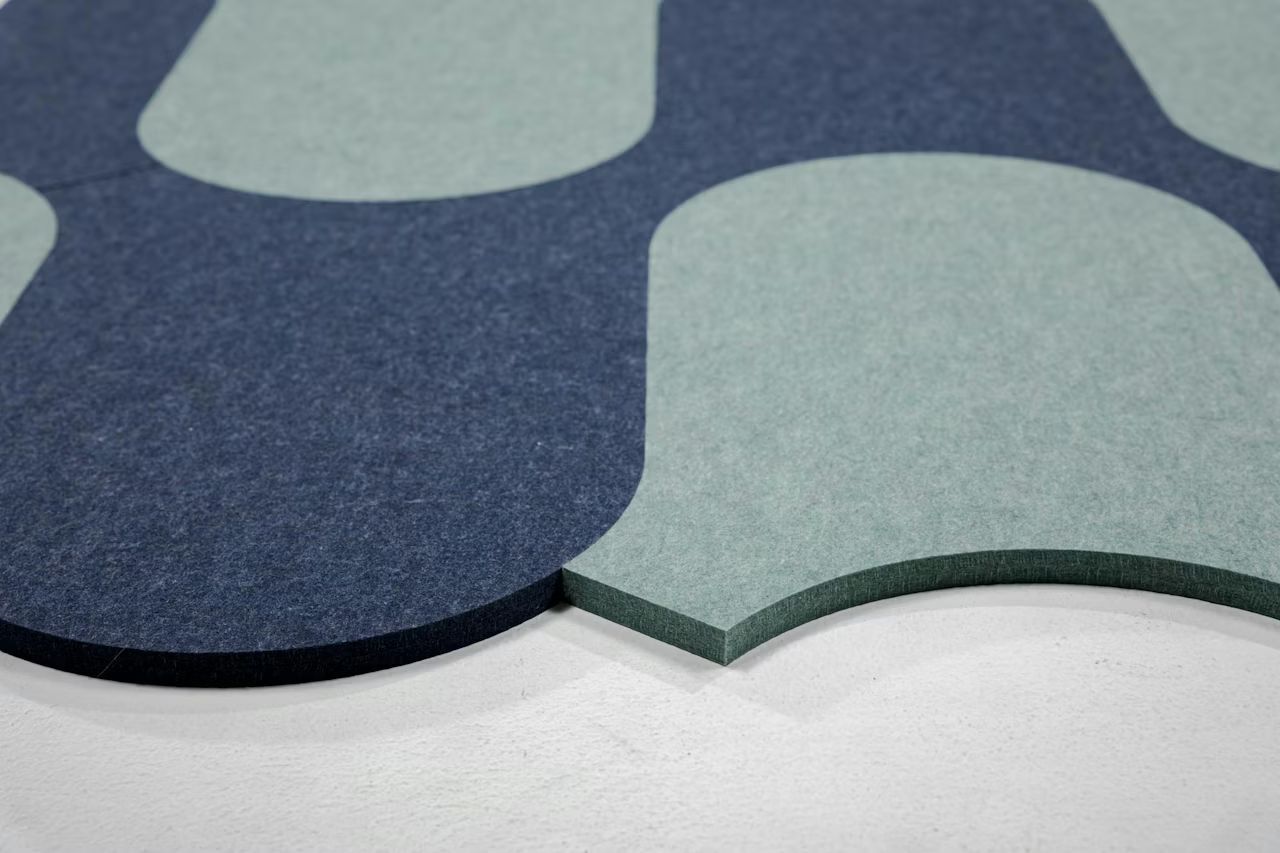 Nahaufnahme bunter, gewölbter Schallschutzplatten in Blau und Grün auf weißem Hintergrund.