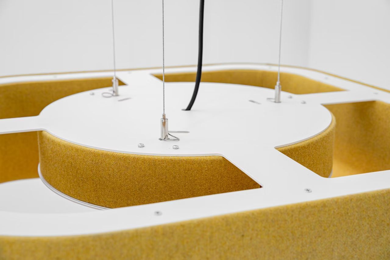 Nahaufnahme einer gelben, hängenden modularen Einheit mit Metallhaltern und Kabel, modernes Design.