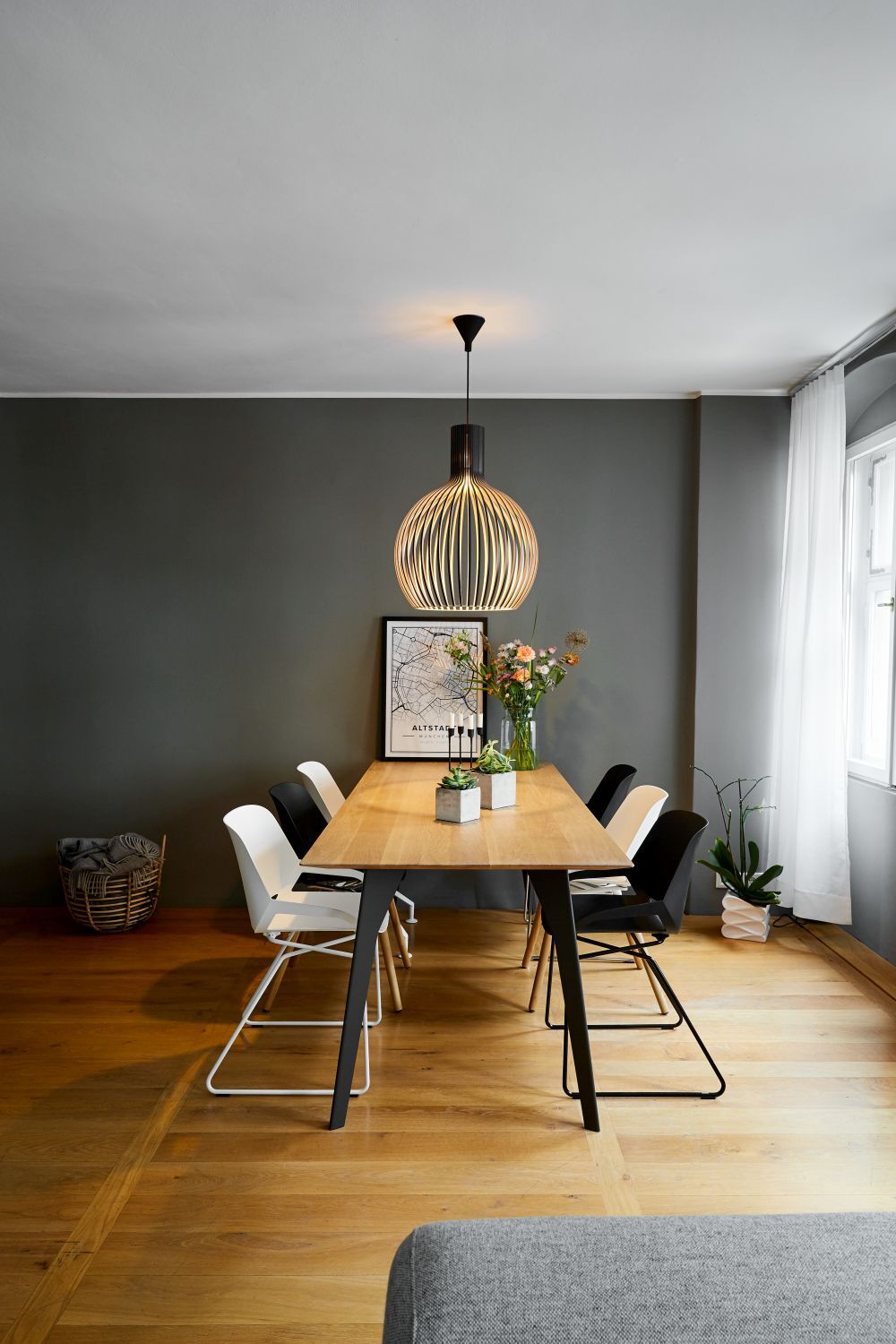 Moderner Essbereich mit Holztisch, stilvollen Stühlen und großer Hängelampe im gemütlichen Raum.