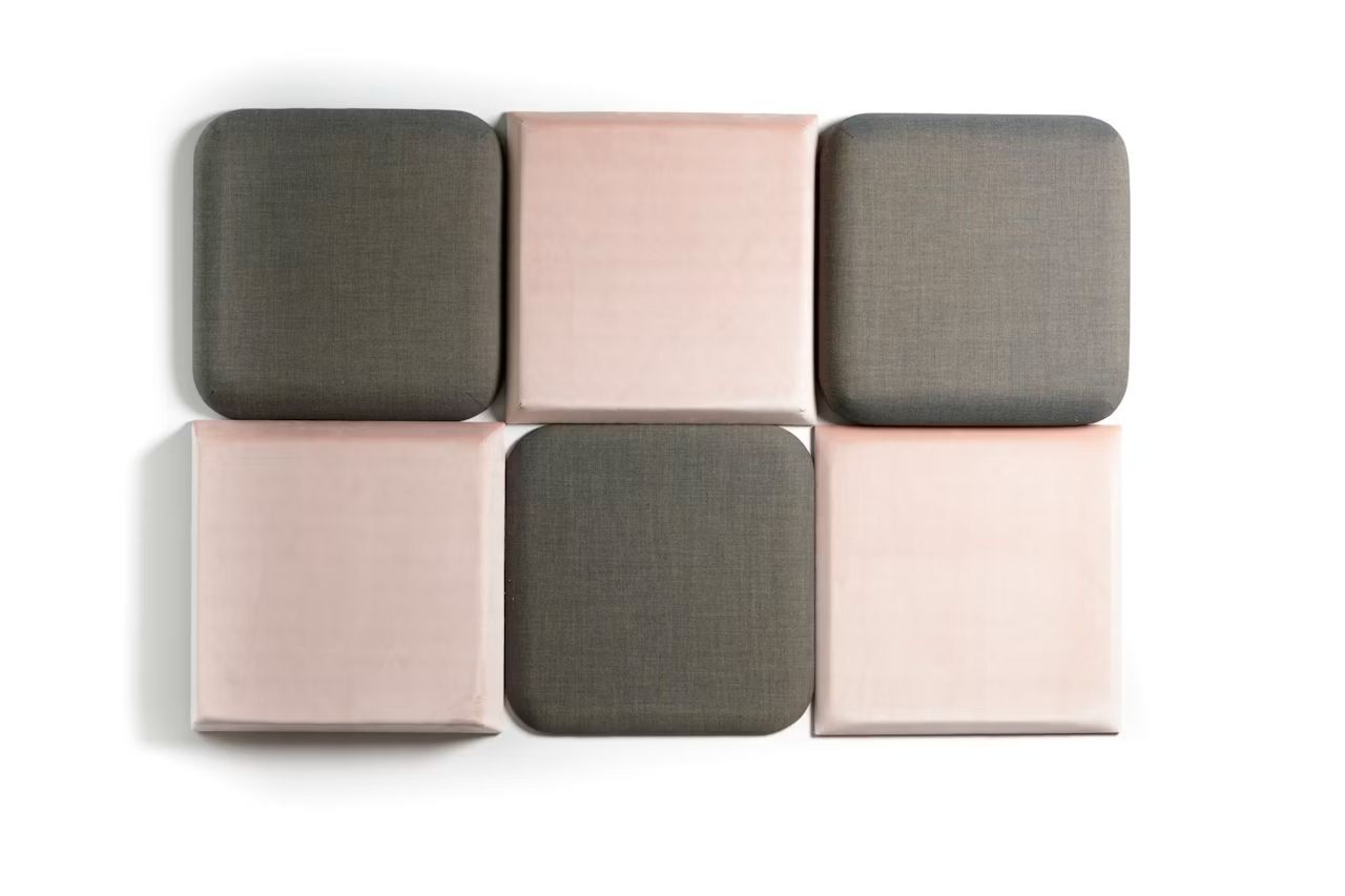 Sechs quadratische Akustikpaneele, abwechselnd in Grau und Rosa, auf weißem Hintergrund angeordnet.