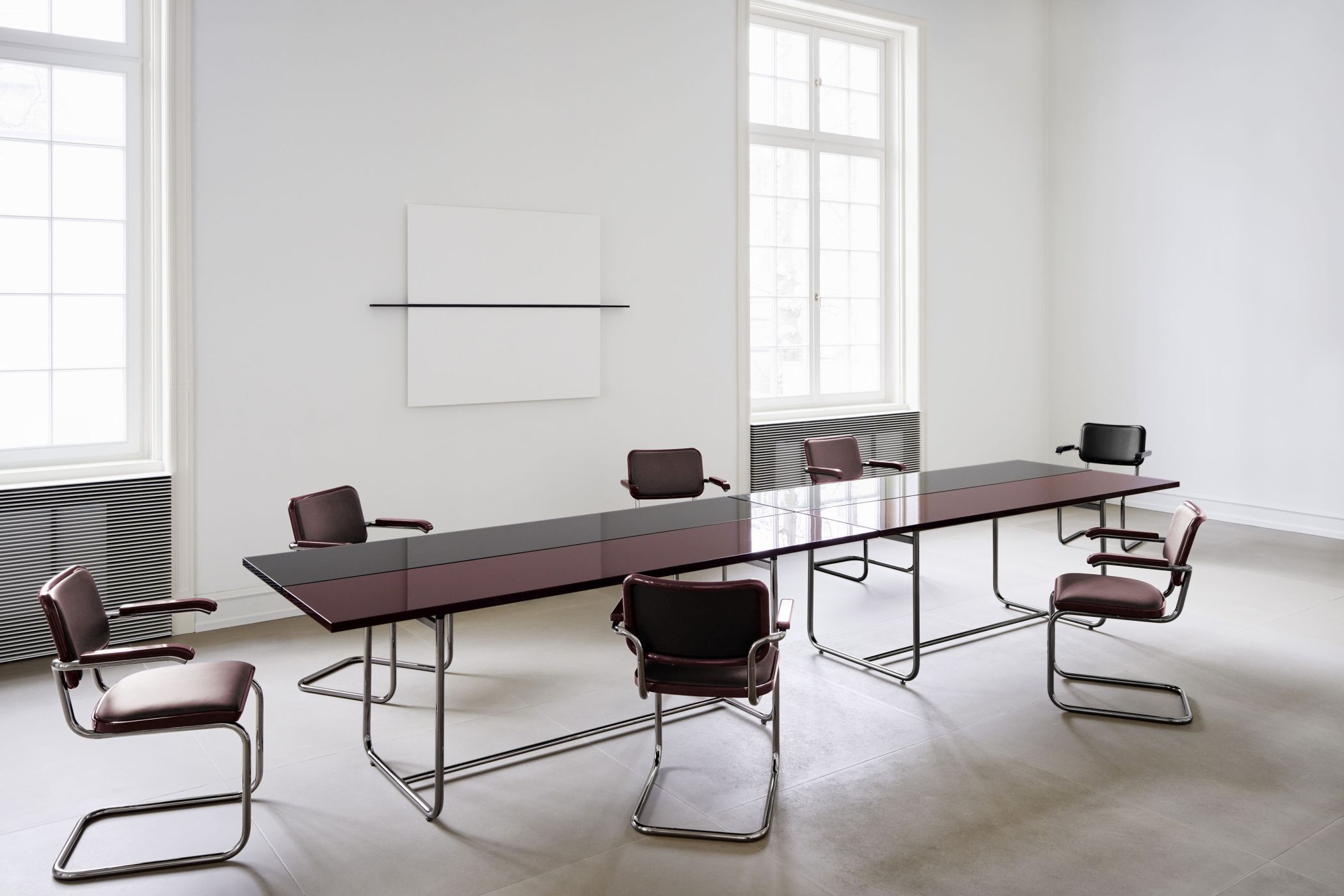 Konferenzraum mit langem, schlanken Tisch und modernen, ergonomischen Freischwingerstühlen in elegantem Design.