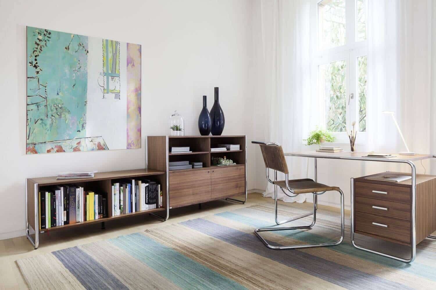 Moderner Arbeitsplatz mit ergonomischem Stuhl, minimalistischen Möbeln und großem Fenster, das natürliches Licht hereinscheint.