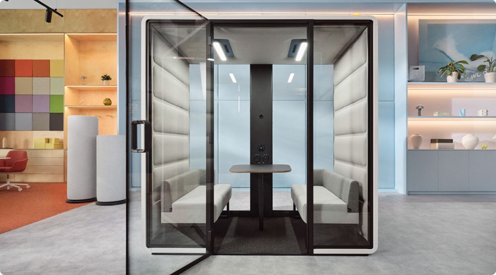Moderne schallisolierte Bürokabine mit Glaswänden und Sitzgelegenheiten, geeignet für Meetings oder konzentriertes Arbeiten.