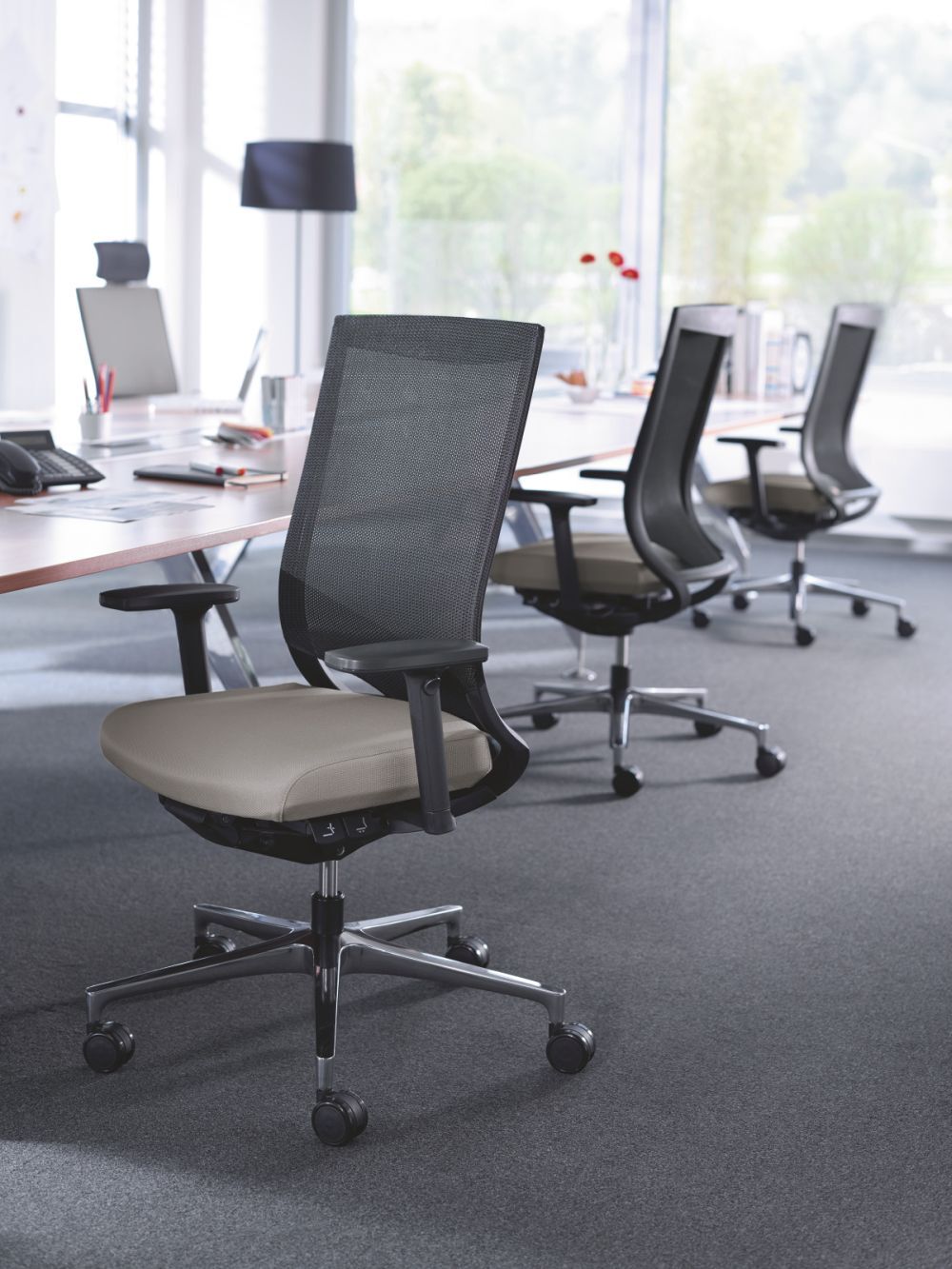 Moderner ergonomischer Bürostuhl mit Netzrückenlehne und gepolstertem Sitz in einem hellen, offenen Büro.