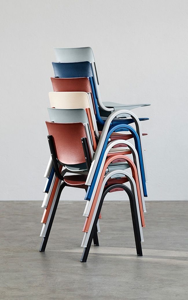 Mehrere ergonomische Stühle in verschiedenen Farben stapeln sich ordentlich auf einem Betonboden.