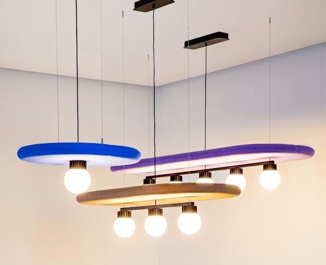 Moderne Hängelampen mit bunten Ringen und Glühbirnen in einem minimalistischen Raumdesign.